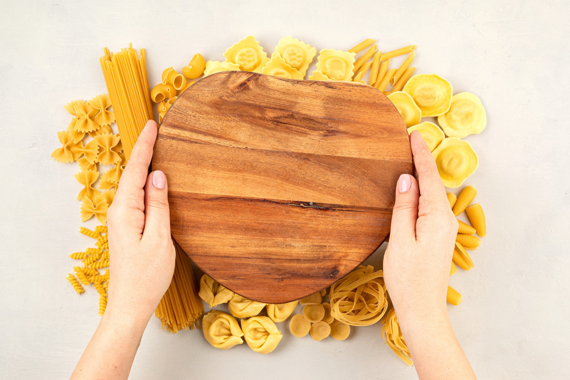 Hands preparing fresh pasta on wooden board