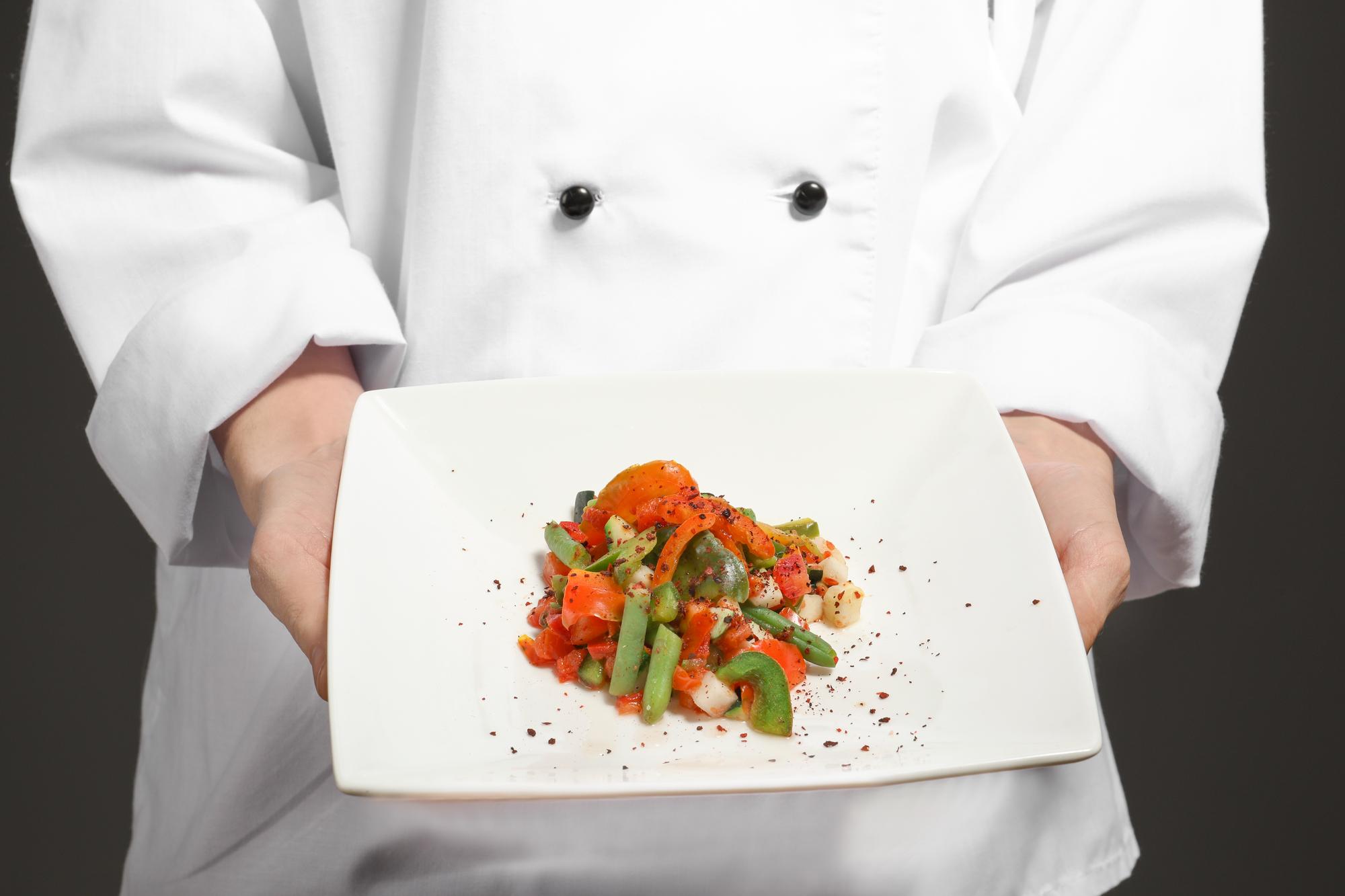 Chef demonstrating plated dish in elegant kitchen